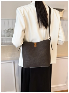 Gros plan du sac seau en cuir marron foncé avec fermoir rotatif doré et texture grainée