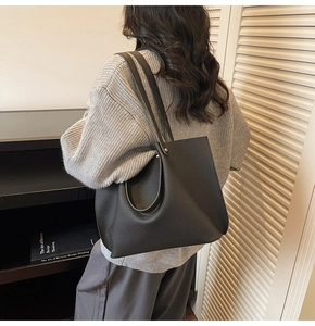 Close-up of black pebble leather tote bag with unique circular handle and dual straps