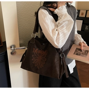 Détail du sac cabas marron foncé avec broderie de marguerite orange et grands anneaux