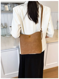 Détail du sac seau marron caramel avec fermoir tournant doré et bandoulière réglable