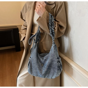 Detail of vintage washed denim hobo bag with ruffled shoulder strap and drawstring pockets