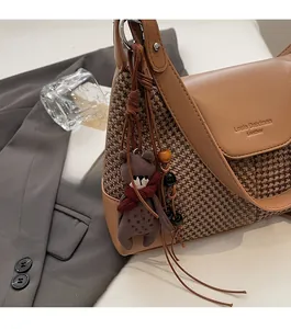Detail of suede crossbody bag featuring brown leather, houndstooth fabric, and bear charm