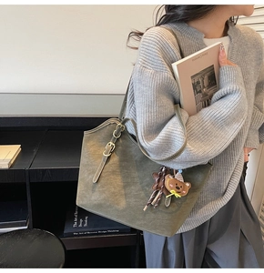 Detail of olive green tote bag featuring adjustable metal buckle and cute bear charm