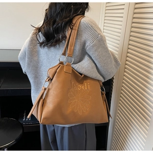 Détail d'un grand sac cabas marron en cuir avec broderie de tournesol et lettrage Maodi