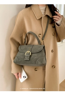 Close-up of retro green crossbody bag with golden horseshoe buckle and textured finish