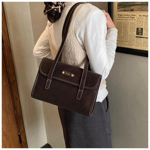 Detail of dark brown retro shoulder bag showing contrast stitching and metal logo plate