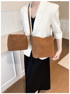 Gros plan du sac seau en daim marron avec fermoir doré et sa pochette assortie