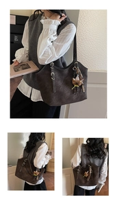 Detail of dark brown tote bag showing contrast stitching, silver buckle and bear charm