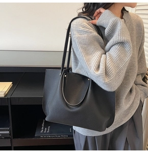 Detail of black pebbled leather tote bag showing soft texture and dual handle design