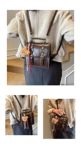 Détail d'un sac à dos vintage en cuir marron avec boucles dorées et breloque ours