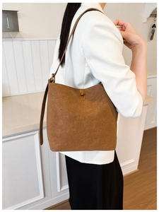 Détail d'un sac seau marron foncé minimaliste avec un fermoir tournant doré élégant