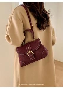 Model wearing a burgundy vintage crossbody bag with contrast stitching over a beige coat