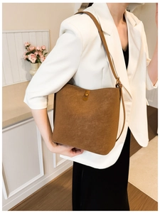 Détail d'un sac seau marron en daim mat avec boucle dorée vintage et bandoulière