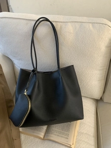 Sac fourre-tout rétro en cuir grainé noir avec pochette sur un canapé beige