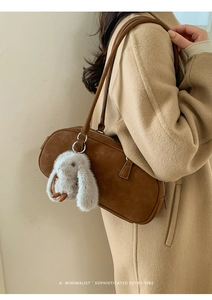 Close-up of brown retro oil wax leather shoulder bag with a cute plush rabbit charm