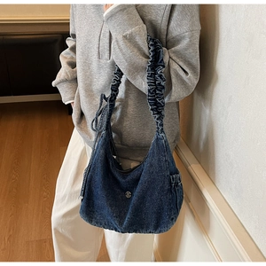 Detail of vintage denim hobo bag with pleated shoulder strap and metallic buckle decoration