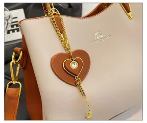 Détail du pendentif en cuir marron en forme de cœur avec strass et pompon doré sur sac