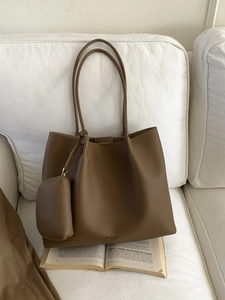 Sac cabas rétro marron en cuir avec pochette sur canapé blanc avec un livre