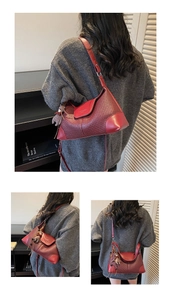 Detail of red-brown woven suede shoulder bag with cute plush bear charm accessory