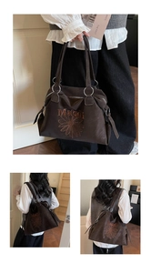 Macro view of a dark brown tote bag featuring sunflower embroidery and silver metal rings