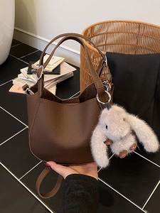 Retro brown lychee leather bucket bag with plush bunny charm and adjustable shoulder strap