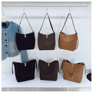 Trois sacs seaux en daim minimalistes noirs et marron avec fermoirs dorés en métal