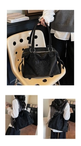 Close-up of black tote bag with daisy embroidery and branding on textured faux leather