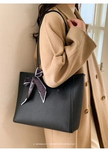 Close-up of black lychee leather tote bag with decorative silk scarf and dual shoulder straps