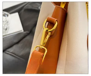 Gros plan sur les ferrures dorées et les coutures d'un sac en cuir beige et orange