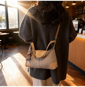 Detail of beige woven shoulder bag with brown leather trim and cute bear charm pendant