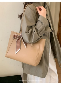 Detail view of khaki leather tote bag with lychee texture and polka dot silk scarf