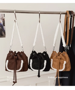 Detail view of plush drawstring bucket bags in various colors with faux fur trim