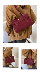 Detail view of burgundy leather messenger bag with white stitching and gold logo