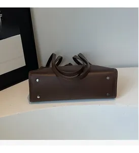 Detailed view of the dark brown leather bag bottom featuring four silver metal feet studs