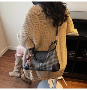 Detail of houndstooth plaid shoulder bag with bear pendant and leather flap accent