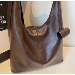 Detail of dark brown faux leather tote bag with smooth texture and vertical stitching