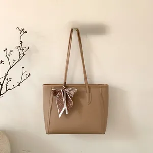 Detail of caramel leather tote bag with elegant polka dot silk scarf on the handle