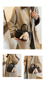Dettaglio della borsa nera con cinturino decorativo e ciondolo a forma di coniglio di peluche