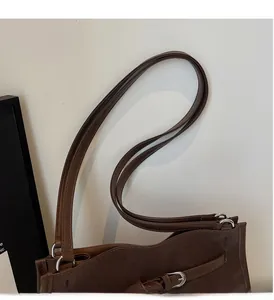 Detail of dark brown tote bag handle with silver metal buckle and stitching