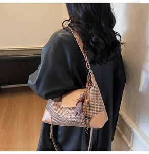 Detail of tan suede shoulder bag featuring tassel charm and woven texture contrast