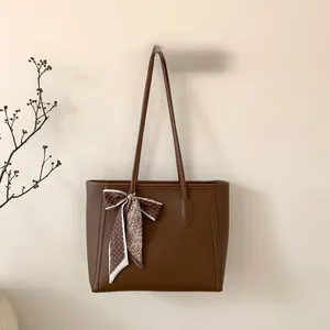 Detail shot of a dark brown lychee leather tote bag with a decorative patterned silk scarf