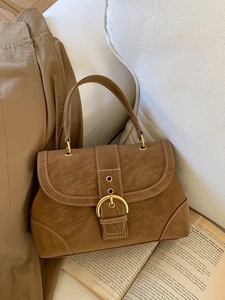 Retro brown textured handbag with contrast stitching and golden clasp on books