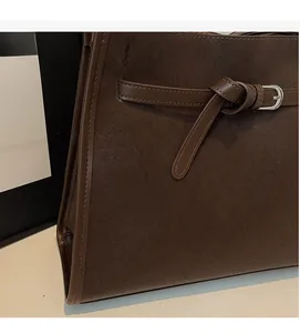 Detail of dark brown matte leather tote bag featuring a vintage silver buckle and stitching