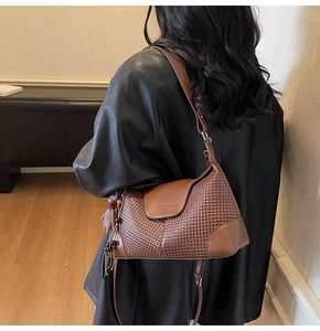 Detail of a brown woven suede shoulder bag with smooth leather flap and fringe tassel