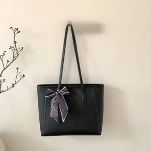 Close-up of black lychee leather tote bag featuring a decorative patterned silk scarf