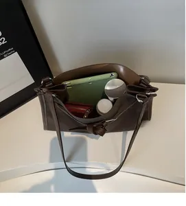 Macro view showing spacious interior of dark brown tote bag with tablet and cosmetics