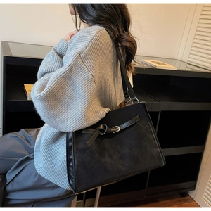 Détail du grand sac cabas noir en daim avec nœud en cuir porté par un mannequin