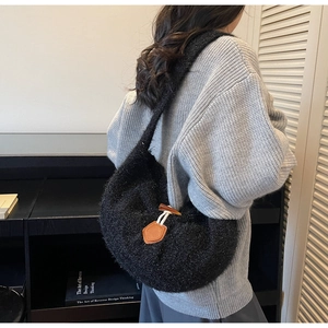 Détail du sac tricoté noir avec empiècement en cuir et fermeture par bouton en corne