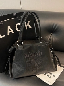 Grand sac cabas noir avec broderie marguerite et logo Maodi sur canapé en cuir