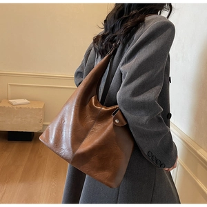 Detail view of large brown leather tote bag showing retro texture and silver stud accent